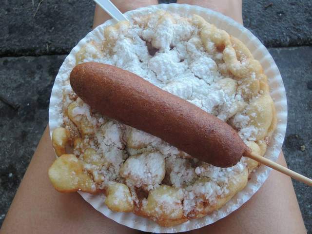 Sitting on a street curb eating a Corn Dog & Funnel Cake.